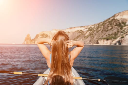 Woman in kayak back view. Happy young woman with long hair floating in transparent kayak on the crystal clear sea. Summer holiday vacation and cheerful female people relaxing having fun on the boat