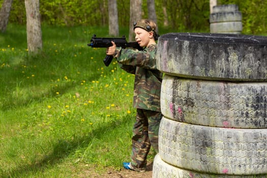 Boy weared in camouflage playing laser tag in special forest playground. Laser Tag is a command military tactical game using safe laser weapons and sensors that record hits.