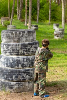 Boy weared in camouflage playing laser tag in special forest playground. Laser Tag is a command military tactical game using safe laser weapons and sensors that record hits.