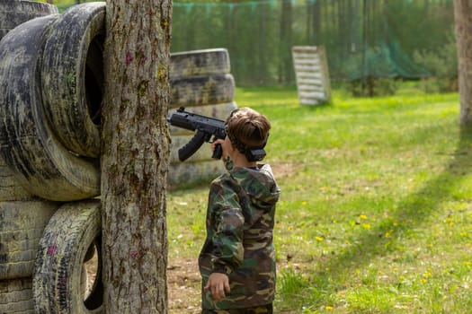 Boy weared in camouflage playing laser tag in special forest playground. Laser Tag is a command military tactical game using safe laser weapons and sensors that record hits.