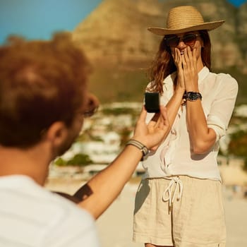 He made her summer extra special. a young woman getting engaged at the beach on a summers day