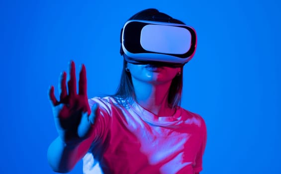 Brunette woman with VR headset touching something what she see in virtual world. Futuristic technology