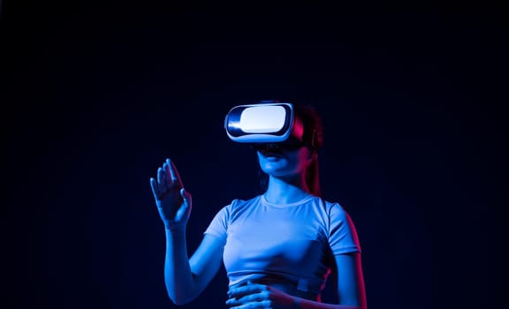 Woman using VR virtual reality glasses headset pointing at objects in metaverse. Virtual reality metaverse