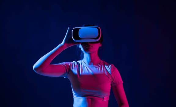 Young woman using the virtual reality headset and interact with a virtual world in a metaverse. Female model wearing VR goggles