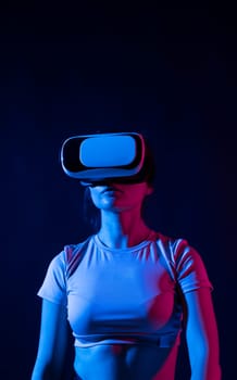 Young woman working in VR goggles on a grey background. Modern architect using virtual reality glasses at workplace. Designer working in augmented reality vr studio