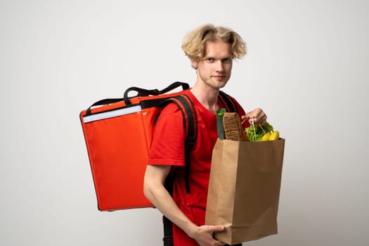 Sive view handsome delivery man, courier carrying package bag of grocery food and drinks from store, supermarket isolated on white studio background