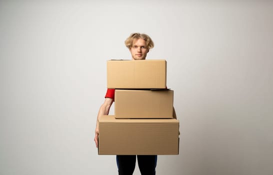 Young delivery man standing with lot of parcel post boxes isolated over white background