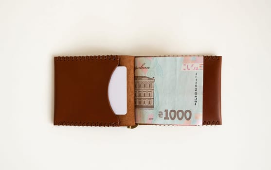 Brown leather money clip, purse with ukrainian hryvnia banknotes. Men's genuine leather wallet. Accessories. Money, financess, economy, saving