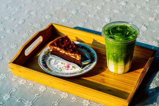 cake and Green tea Latte on outdoor wooden table in sunshine morning