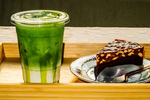 cake and Green tea Latte on outdoor wooden table in sunshine morning