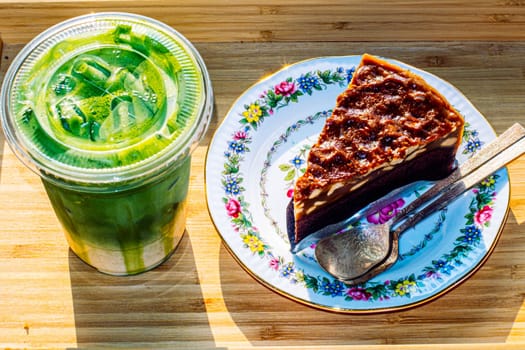 cake and Green tea Latte on outdoor wooden table in sunshine morning
