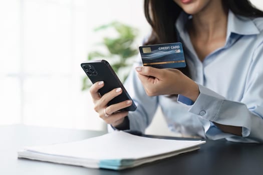 Woman holding credit card and using mobile phone. Online payment, Internet banking, Shopping online.