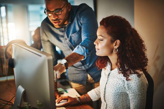 The experts in productivity. a young businessman and businesswoman using a computer together during a late night at work