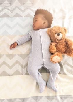 Top view, bed and baby sleeping with teddy bear for rest, nap time and dreaming in nursery. Childcare, newborn and cute, tired and African child in bedroom sleep for comfort, relax and calm at home.