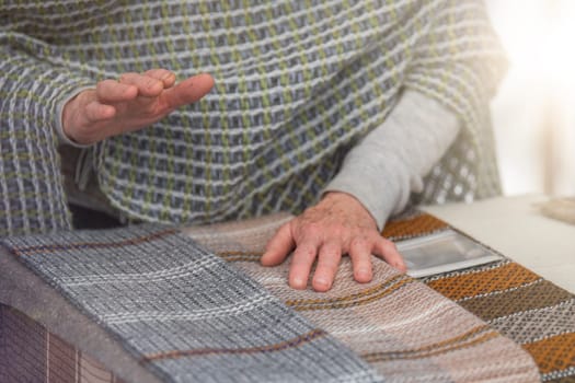 An elderly woman sells knitted items of her own production. Small business concept. High quality photo