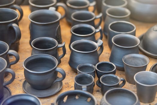 Products from black ceramics of handwork. The craftsman sells many ceramic pots in the market. The concept of a small business for the production of dishes. High quality photo