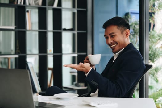 Portrait of a business man talking on the computer and drinking coffee