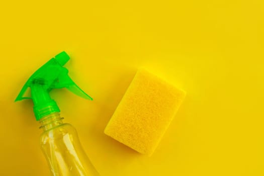 Cleaning. Flat lay Bottle with cleaning product and sponge on yellow background. Cleaning supplies, top view.