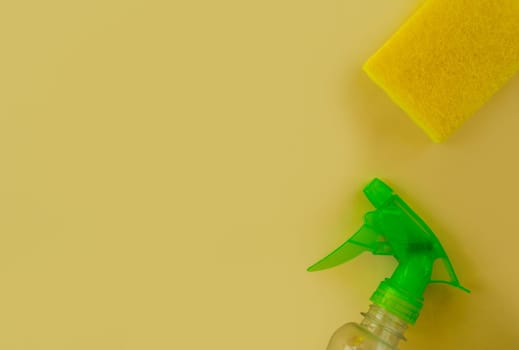 Cleaning. Flat lay Bottle with cleaning product, sponge against yellow background. Cleaning supplies, top view.