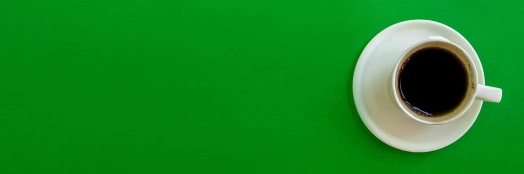 Banner.  A cup of coffee on a green background. A cup of coffee with a saucer on a green background, top view.