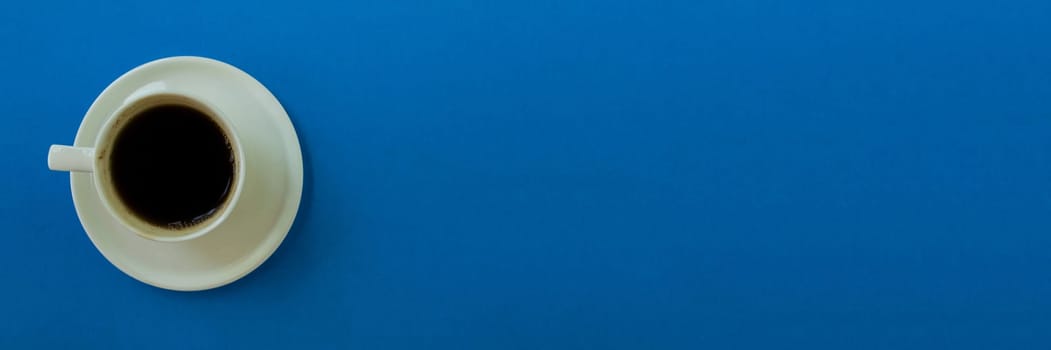 Banner.  Cup of coffee on a blue background. Cup of coffee with a saucer on a blue background, top view.