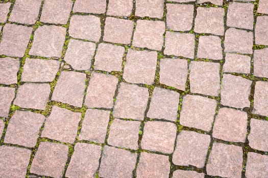 The road is paved with decorative stone. The old road of granite paving stones.