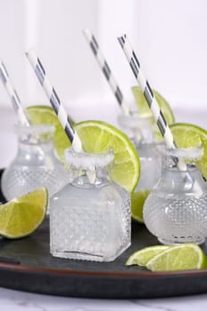 Classic alcoholic cocktail Margarita. Served in mini bottles with salt and lime. An original idea for a buffet event.