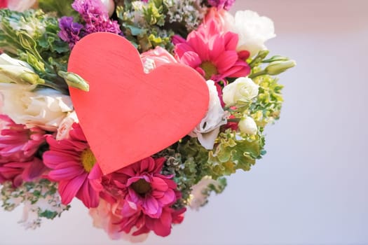 Valentine's day elegant bouquet with roses flowers, Lisianthus, chrysanthemum and red wooden heart, sign of love.
