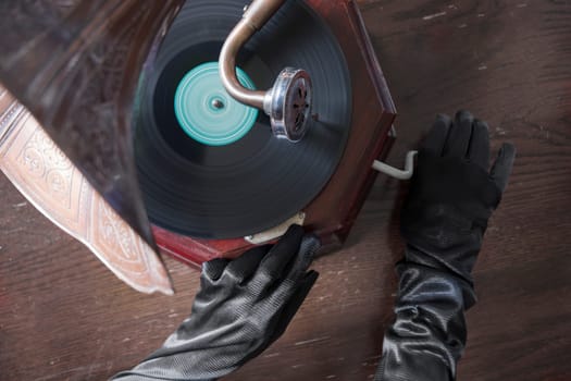 Ghostly hands in black gloves turn the handle of an old gramophone. Horrible Halloween holiday. High quality photo
