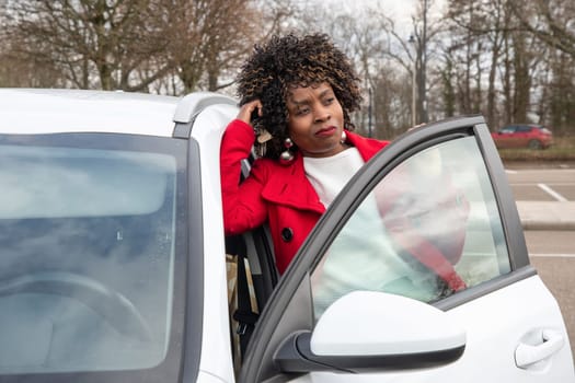 African american beautiful woman in a red coat posing on the street against the background of a white car, High quality photo