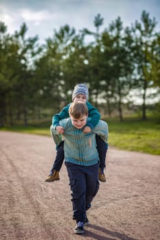 Two funny boys-brother and friend, walking together in the spring park, running, jumping and enjoying. Happy, joyful family.