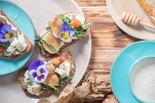 delicious bruschetta with homemade bread, garnished with fig,soft cheese,pansies, top view. High quality photo