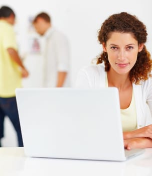 Pretty business woman using laptop. Portrait of pretty business woman using laptop with colleagues in background