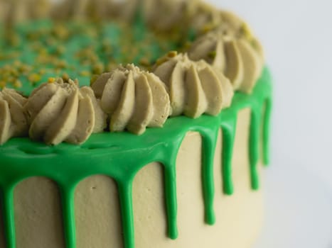 studio shot of green pistachio frosted dripped icing cup cake