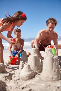 Their favorite form of beach fun. a happy family building sandcastles together at the beach