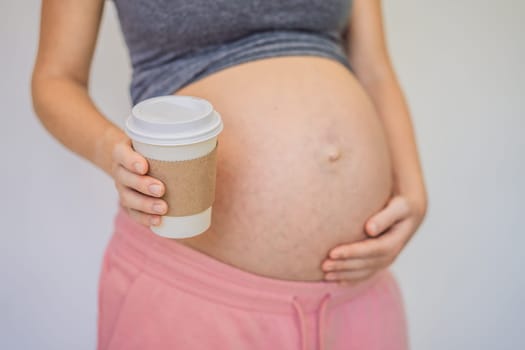 A pregnant woman holds a cup of coffee in her hands. Caffeine safety, myths about coffee during pregnancy concept.