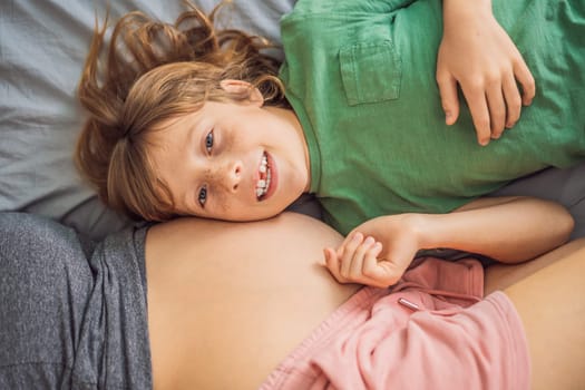 Young beautiful pregnant woman and eldest son. The cute boy leaned his ear against his mother's belly. Expecting a baby in the family concept. Preparing an older child for a younger one.