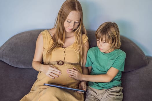 pregnant mom and son look at the tablet. Reading a book or watching a cartoon or making a video call. Look at the photo from the ultrasound.