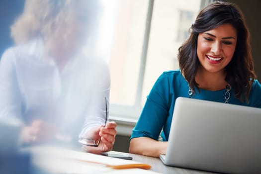 Using technology to support their business initiative. two businesswomen using a laptop together in an office