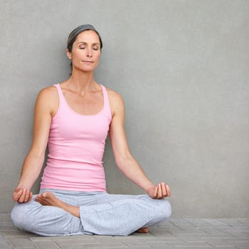 Focussed on achieving greater wellbeing. an attractive mature woman practicing yoga in the lotus position