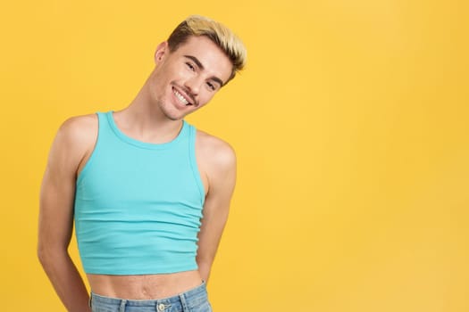 Caucasian handsome gay man smiling at camera in studio with yellow background