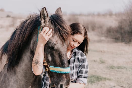 Cute happy young woman with horse. Rider female drives her horse in nature on evening sunset light background. Concept of outdoor riding, sports and recreation.