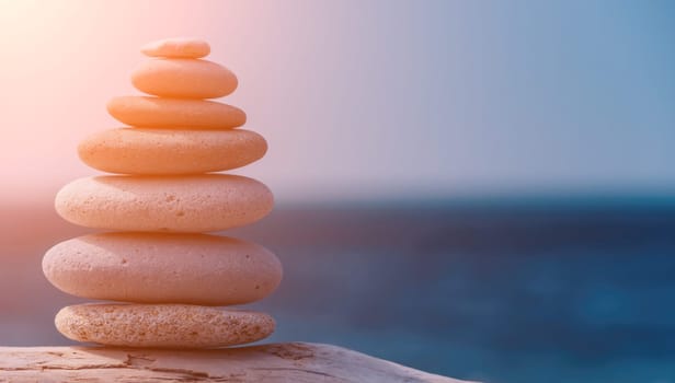 Balanced Pebbles Pyramid on the Beach on Sunny Day and Clear Sky at Sunset. Blue Sea on Background Selective focus, zen stones on sea beach, meditation, spa, harmony, calm, balance concept.