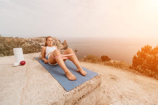 Woman sea pilates. Sporty, middle-aged woman practicing pilates in park near the sea. trains on a yoga mat and exudes a happy and active demeanor, promoting the idea of a healthy lifestyle through exercise and meditation.