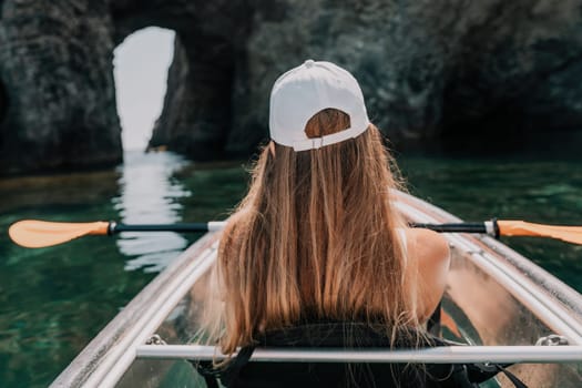 Woman in kayak back view. Happy young woman with long hair floating in transparent kayak on the crystal clear sea. Summer holiday vacation and cheerful female people having fun on the boat.