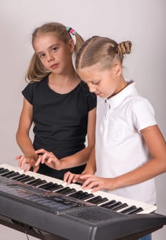 Music class in school or at home. Two girls playing piano. Kids play music. Classical education for children. art lesson. Little girl at digital keyboard. Instrument for young student.