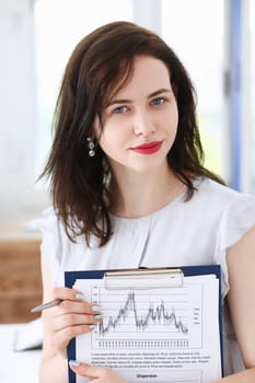 Beautiful smiling cheerful girl at workplace look in camera with colleagues group in background. White collar worker at workspace job offer modern lifestyle client visit profession train concept