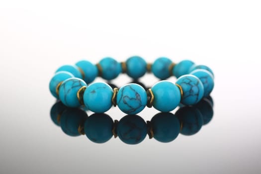 Bracelet of bijouterie jewelry made of turquoise and gold on a gray black background