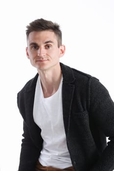 Portrait of an attractive man in a sweater and a T-shirt, sitting on a chair and smiling