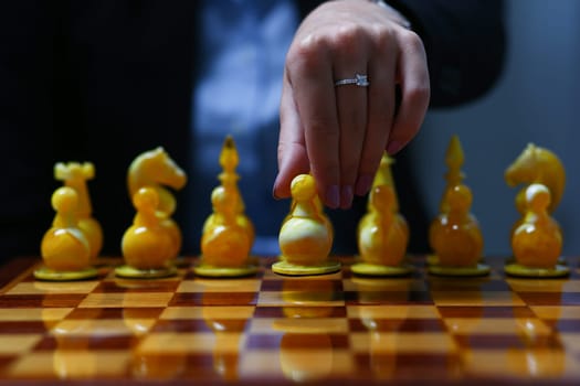 Female hand holding a business woman holding a chess piece. Makes the first move in the business strategy